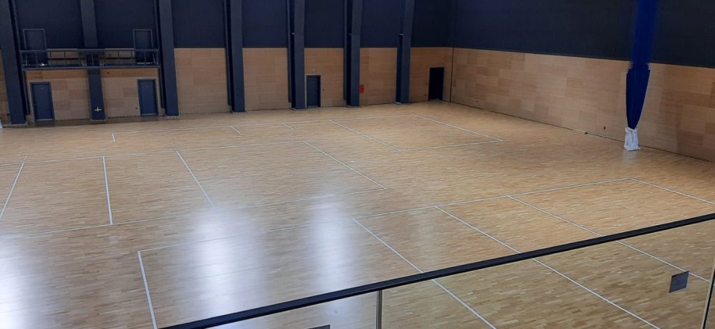 Freshly sanded school gym floor in London with professionally added court lines for basketball and badminton.