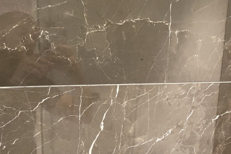 Brown Emperador marble before and after polishing - dramatic restoration result in London Brown Emperador marble before and after polishing – left side dull and worn, right side restored to deep rich brown with enhanced veining and high-gloss finish.
