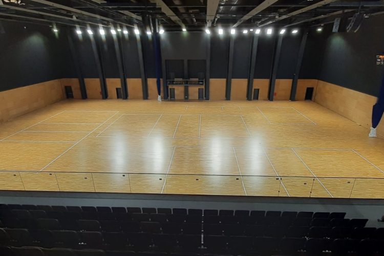 School assembly hall in London mid-way through professional dustless sanding – floor stripped back to bare wood, ready for commercial lacquer application.